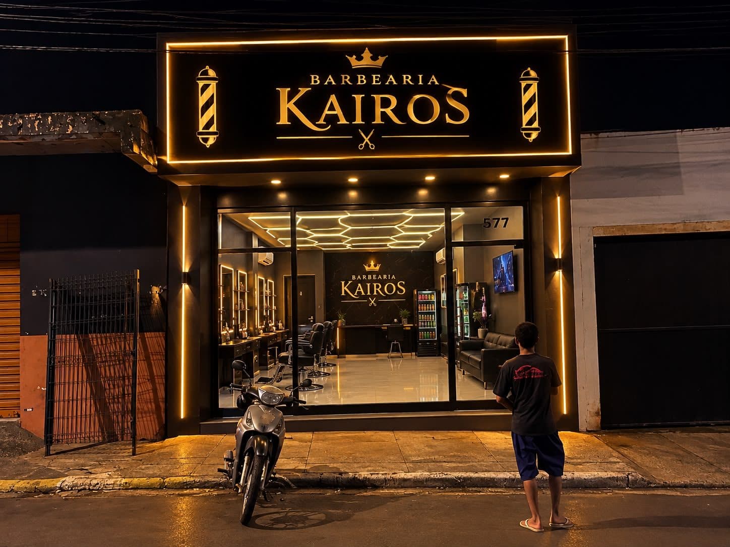 Fachada da Barbearia Kairos iluminada à noite